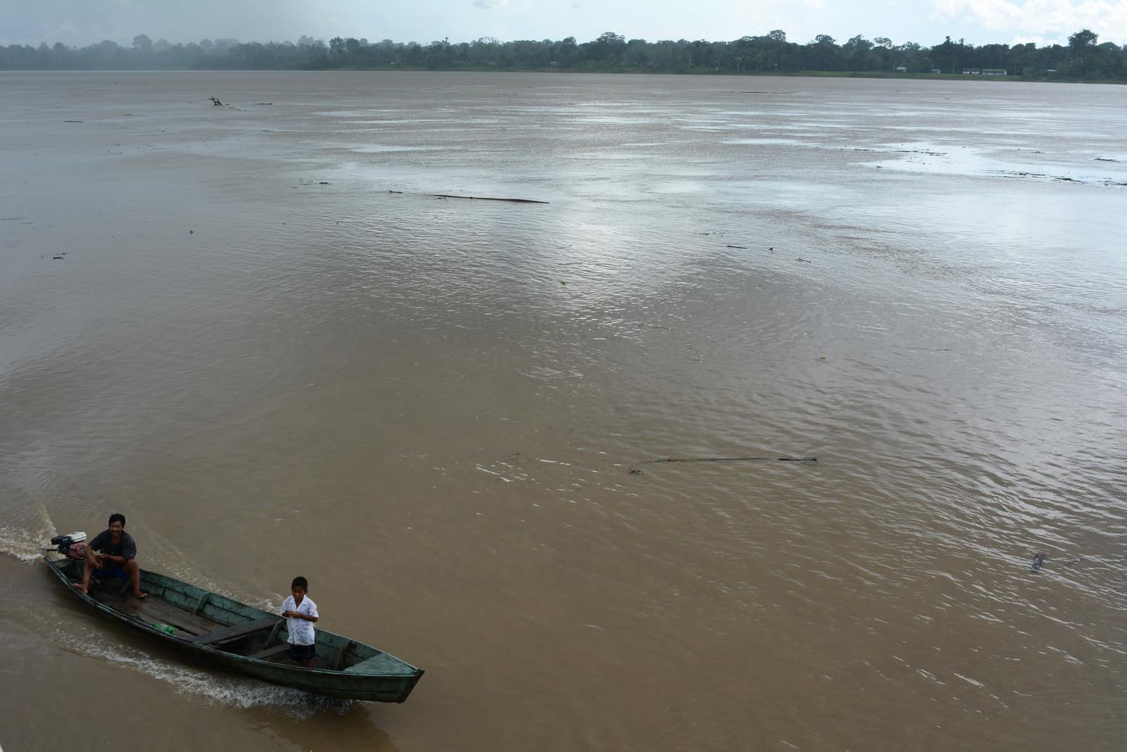 A dugout working a wide brown reach of the Colombian Amazon.