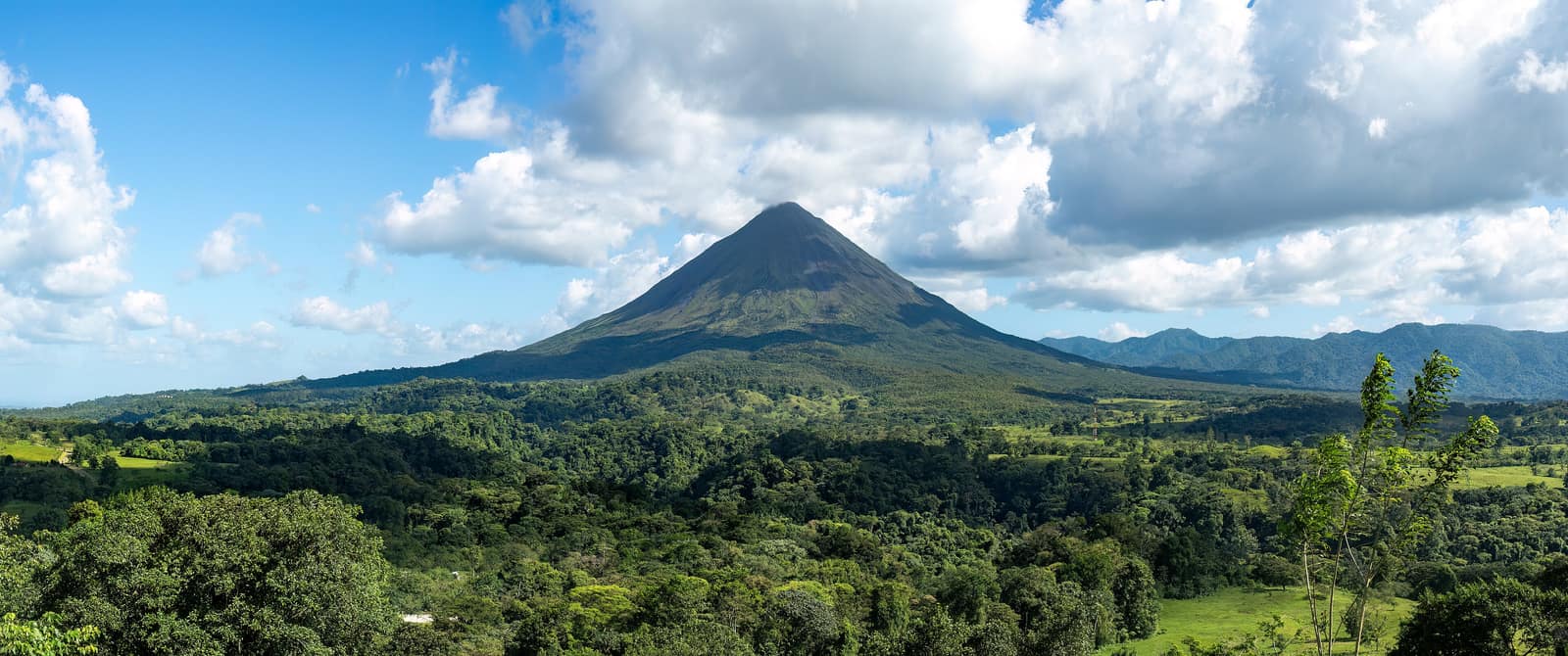 Arenal's cone under cloud above the lake.