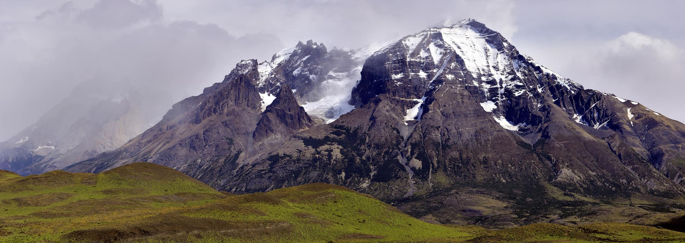 The Paine massif under moving cloud, its granite towers rising above the Patagonian steppe.