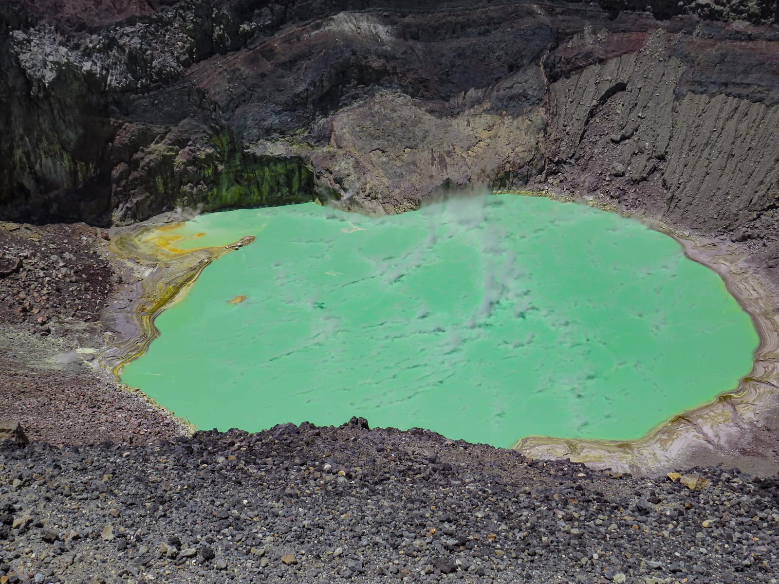 The green crater lake inside Ilamatepec, steam moving across the water.